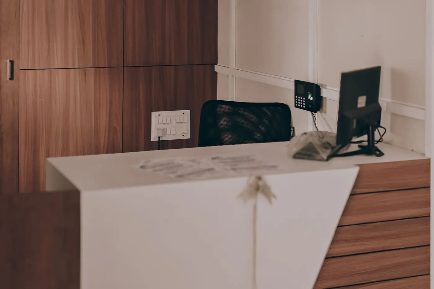Recepción de la clínica, con mostrador de madera clara y luz natural
