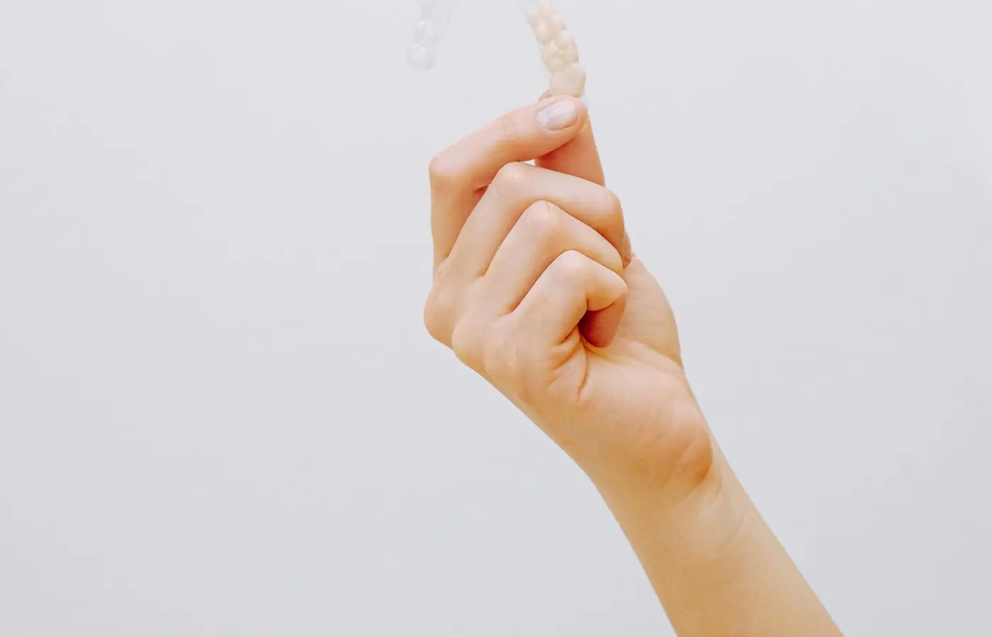 Alineador dental transparente sostenido con la mano en la clínica antes de colocarlo